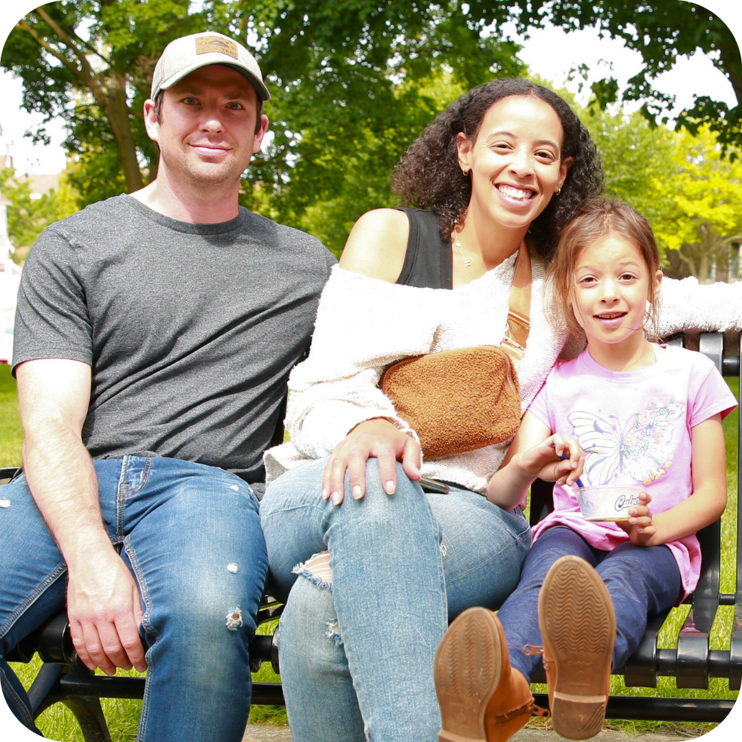 image of family sitting in a park and smiling on a sunny day